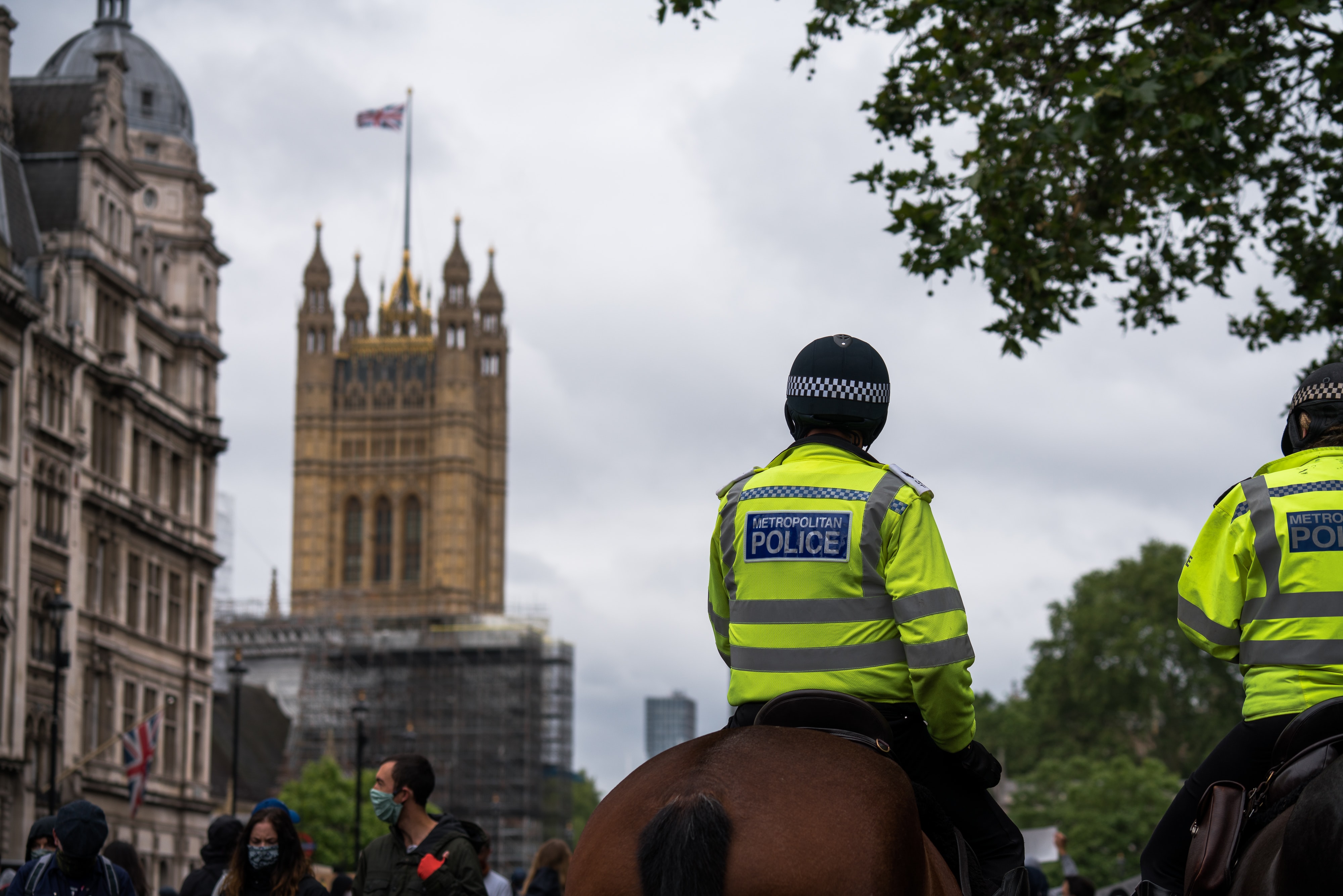 A Metropolitan Police officer on horseback, seen from behind in front of the Palace of Westminster